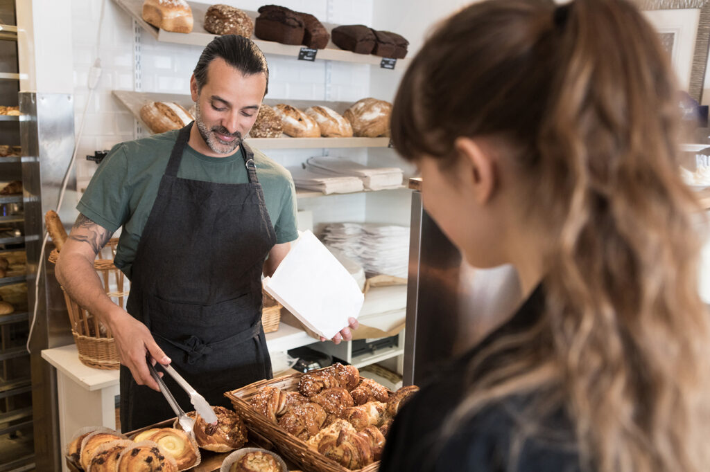 Kellner holt Croissant für Kunden ab