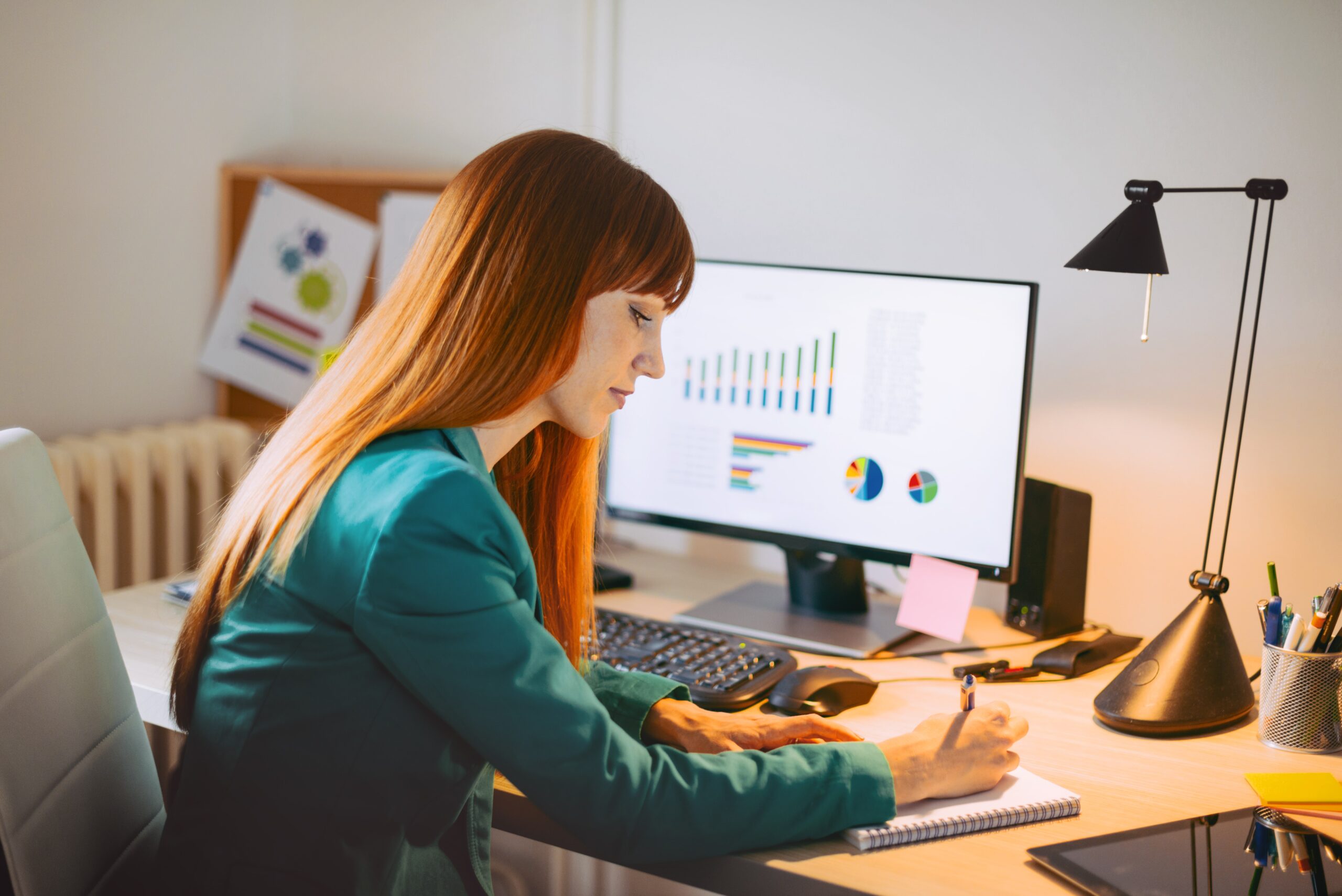 Professionell sitzt am Schreibtisch mit Computer und unter der Lampe und arbeitet fleißig an Finanzberichten