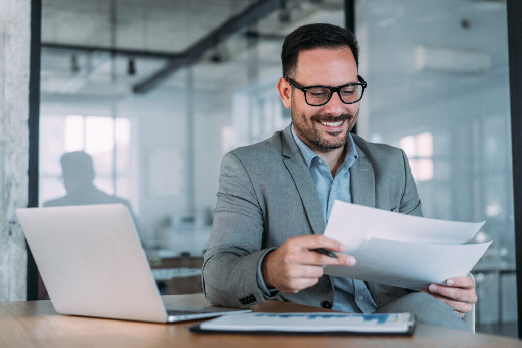 Shot of smiling business professional reading a document at their desk in an office.