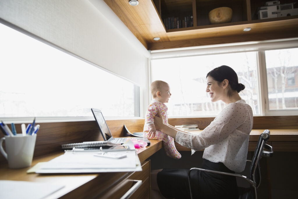 Mother smiling at baby in front of laptop
