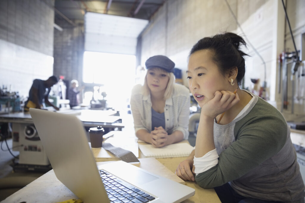 Two people in the office both looking at the same computer screen