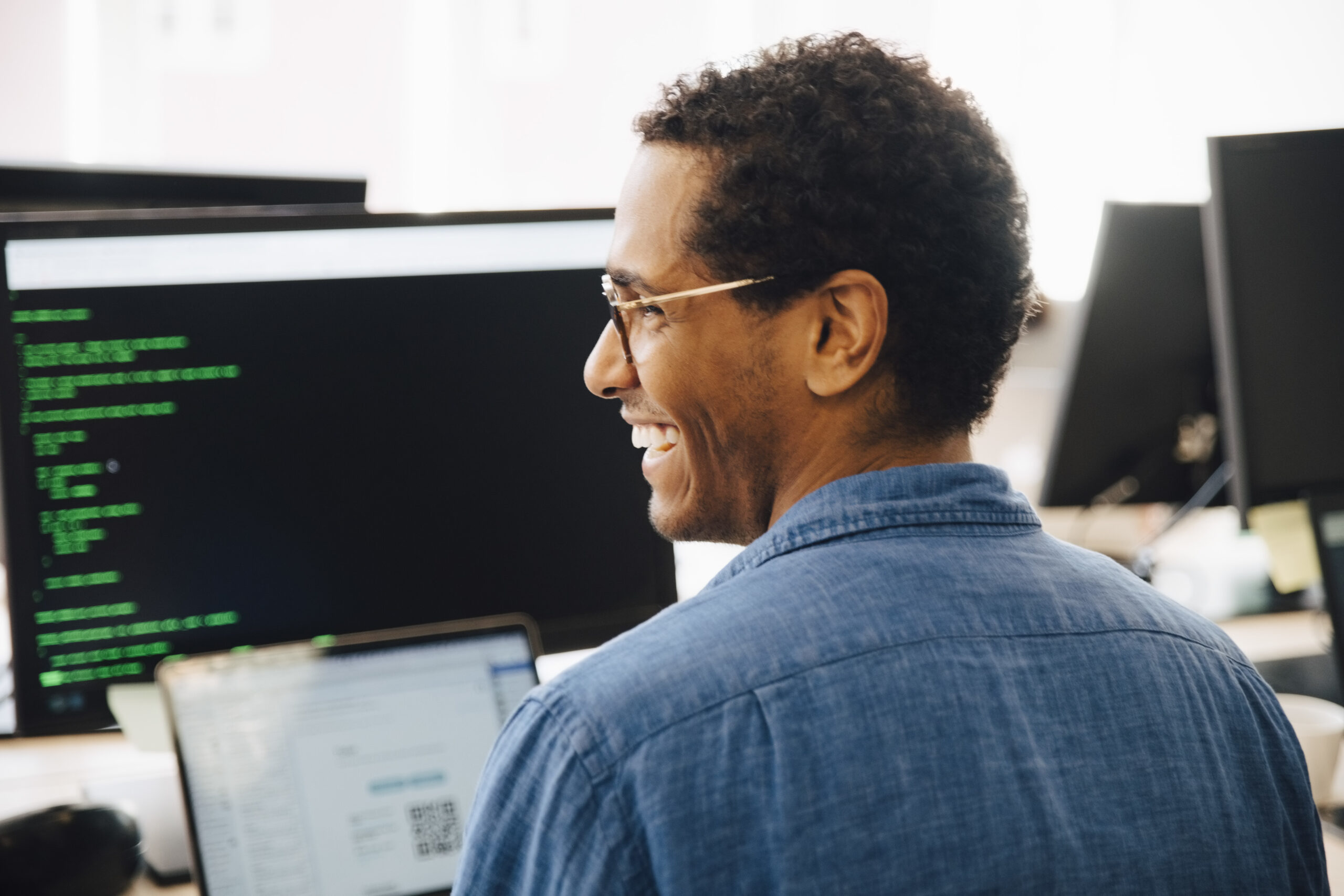 Person smiling in front of computer screen in office