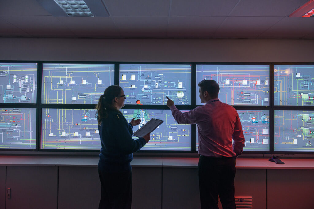 Two people looking at a series of computer displays