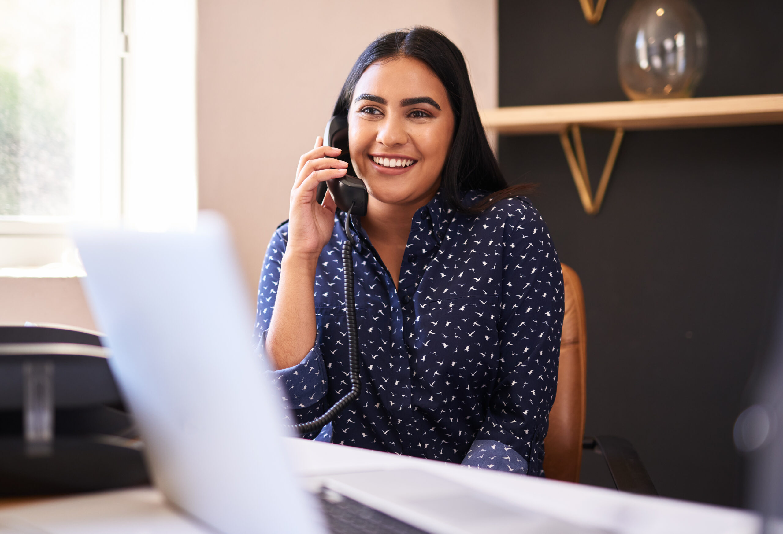 Young person smiling in office while talking on the phone